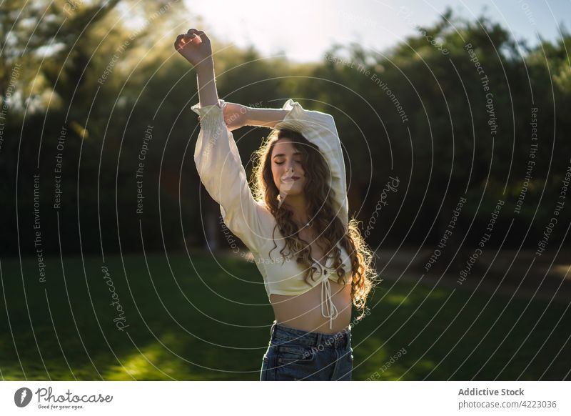 Attraktive Frau steht in sonnigen üppigen Park Stil pflanzlich Rasen trendy feminin Anmut Wiese Garten Natur ruhig grasbewachsen jung Gelassenheit Windstille