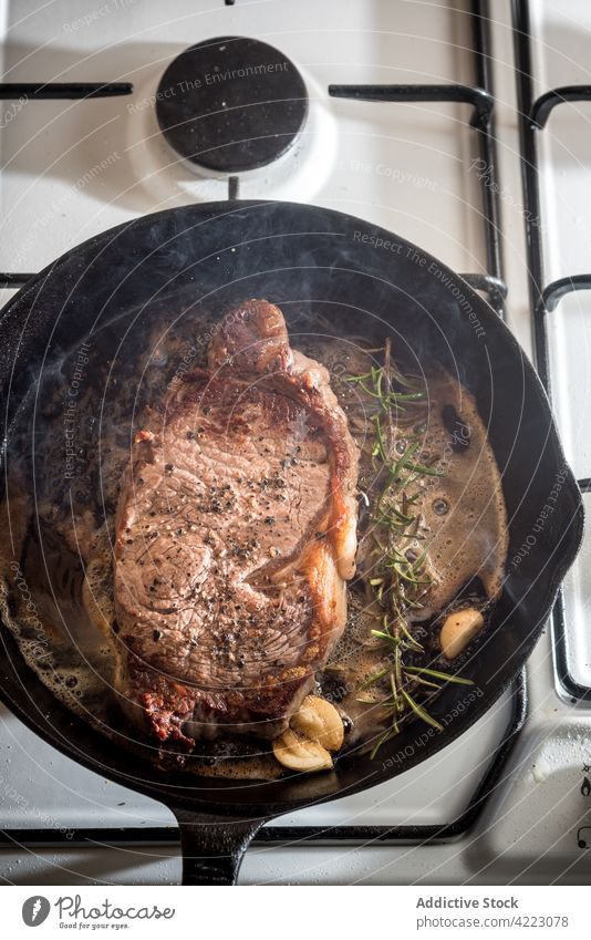 Bratpfanne mit leckerem Rindersteak und Gewürzen Pfanne Steak Fleisch Rindfleisch appetitlich braten Rosmarin Knoblauch Herd Gas Aroma Verdunstung Butter