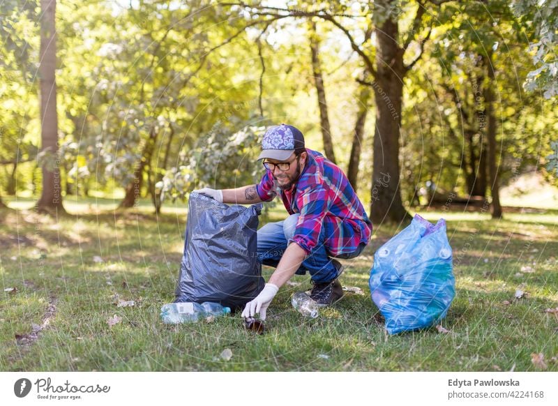 Junger Mann beim Aufsammeln von Müll in seinem örtlichen Park laufen wandern Wald Gras natürlich Landschaft Umwelt Baum außerhalb männlich Person Tag im Freien