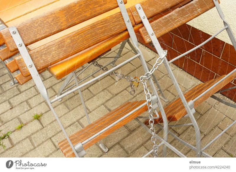 Holzstühle und Tisch im Biergarten sind mit einer Kette und einem Schloss versehen / geschlossen Holzstuhl Holztisch Stuhl Cafe Außenbereich Corona