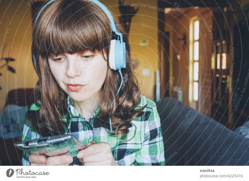 Junge Frau zu Hause, die Musik genießt heimwärts im Innenbereich Freizeit Technik & Technologie Telefon Smartphone Gerät Kopfhörer jung Jugend Teenager Freude