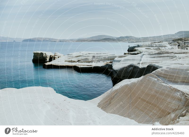 Felsige, unebene Küste, umspült von kräuselndem Meer Meeresufer kurvenreich Natur felsig MEER malerisch Strandpromenade sarakiniko Milos Blauer Himmel rau Ufer