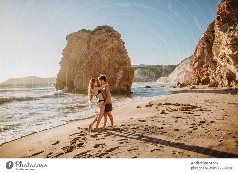 Junges Paar, das sich an der sonnigen Felsenküste umarmt Umarmung Meeresküste verliebt Partnerschaft Natur Strand Flitterwochen romantisch Resort Umarmen