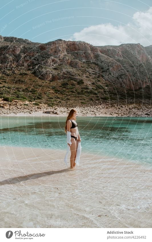 Attraktive Frau in Badekleidung steht am sandigen Meeresufer Kälte Balos Strand Badeanzug Felsen Resort Paradies malerisch Bräune ruhen Bikini Crete schlank