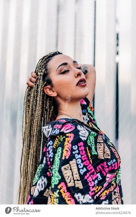 Frau mit Make-up berührt Haar auf der Straße der Stadt Streetstyle Mode cool Individualität Haare berühren Geflecht Porträt Zeitgenosse Generation modern