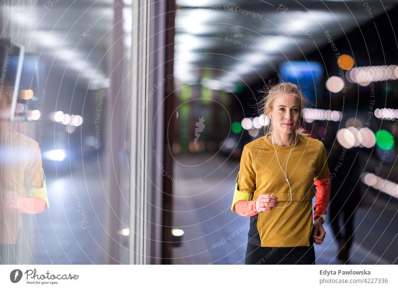 Weibliche Läuferin in der Stadt bei Nacht Jogger Joggen rennen Energie Übung Bekleidung trainiert. Fitness Erholung Sport Aktivität Vitalität Körper