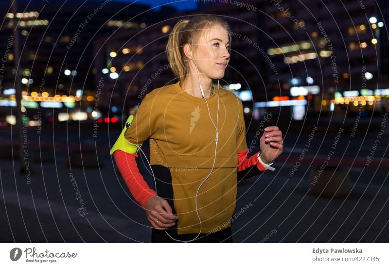 Weibliche Läuferin in der Stadt bei Nacht Jogger Joggen rennen Energie Übung Bekleidung trainiert. Fitness Erholung Sport Aktivität Vitalität Körper