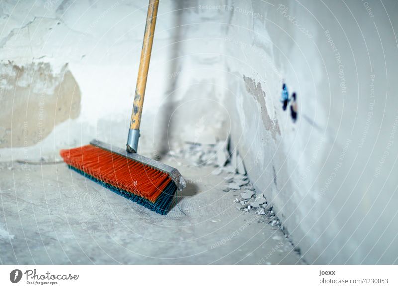 Besen mit roten und blauen Borsten steht in Ecke auf einer Baustelle Wand Elektroinstallation Arbeit & Erwerbstätigkeit Menschenleer Renovieren Handwerk