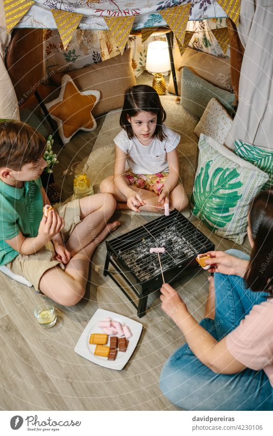 Familie bei der Zubereitung von S'mores mit Grill zu Hause Antenne Herstellung Rauchwaren Marshmallow Röstung kleiner Grill Camping zu Hause staycation