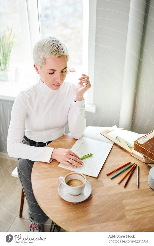 Astrologe schreibt in ein Notizbuch am Tisch im Haus schreiben Notebook vorhersagen Zukunft Horoskop Astrologie Pseudowissenschaft Frau glänzend