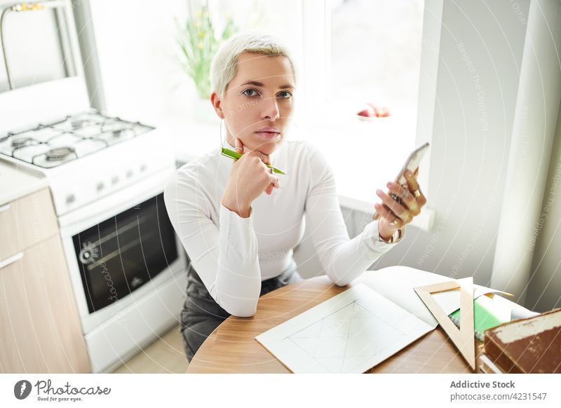 Astrologe mit Smartphone beim Zeichnen auf Papier zu Hause zeichnen Astrologie Pseudowissenschaft göttlich vorhersagen Zukunft Frau Funktelefon heimwärts Tisch