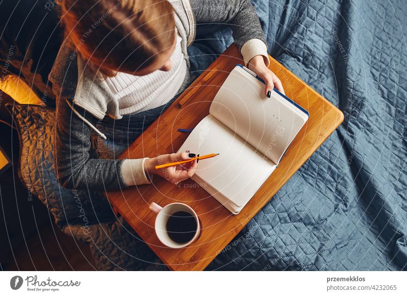 Schüler lernen zu Hause. Junge Frau macht Notizen, Lesen und Lernen von Notizblock. Mädchen schreiben Journal sitzen im Bett Bildung im Innenbereich arbeiten