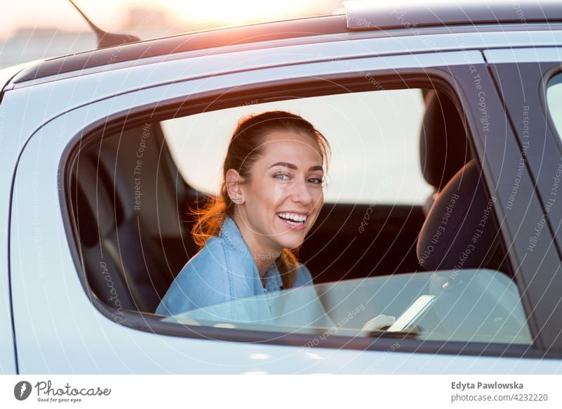 Junge Frau mit Smartphone auf dem Rücksitz eines Autos Carsharing selbstbewusst Lächeln Befriedigung attraktiv schön junger Erwachsener Freude positiv Inhalt