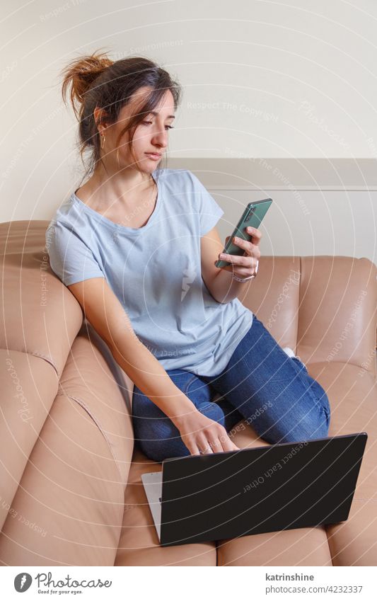 Junge Frauen arbeiten mit Laptop und mit Handy sitzen auf dem Sofa jung anhaben Attrappe T-Shirt lernen Schüler Lifestyle Jeanshose Kaffee zum Mitnehmen Tasse