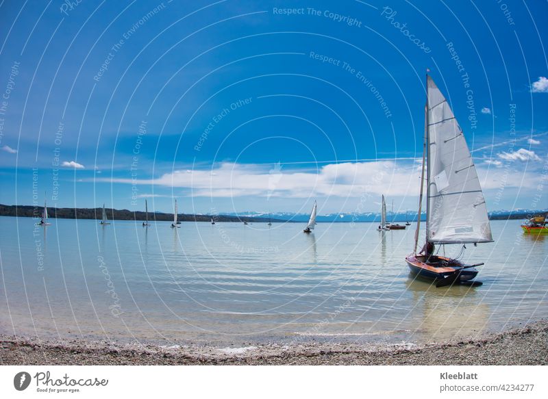 Segelboote werden am Ammersee zu Wasser gelassen - Auszeit und Erholung bei schönem Frühlingswetter Berge Himmel blau zahrte Wolken klares Wasser Sport