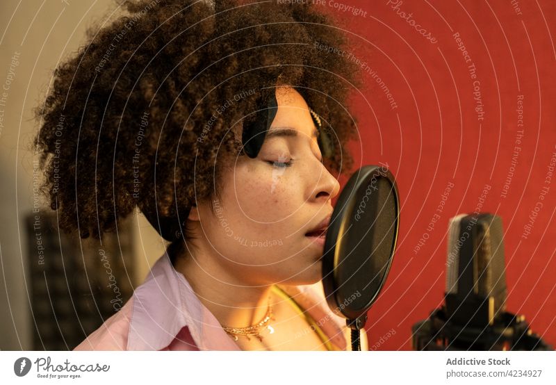 Afroamerikanischer Sänger, der im Aufnahmestudio ein Lied ins Mikrofon singt Gesang Aufzeichnen Musik professionell Atelier Frau Sängerin singen Pop-Filter