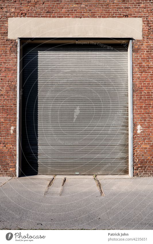 Rolltor in einer alten Industriehalle aus Bachstein. Tor Garagentor Fassade Lastkraftwagen Baustein Menschenleer Gebäude zugeklappt Lagerhalle Einfahrt