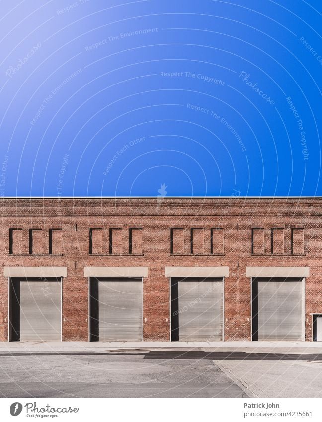 Rolltor in einer alten Industriehalle aus Bachstein. Tor Garagentor Fassade Lastkraftwagen Menschenleer Gebäude Lagerhalle Einfahrt Außenaufnahme Blauer Himmel