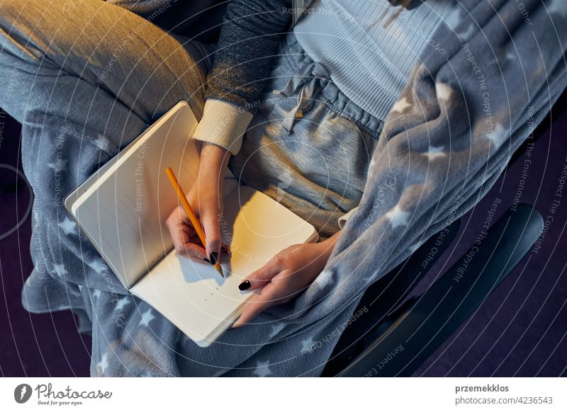 Schüler beim Lernen zu Hause. Junge Frau macht sich Notizen, liest und lernt vom Notizblock Bildung im Innenbereich arbeiten Person Hinweis Notebook studierend