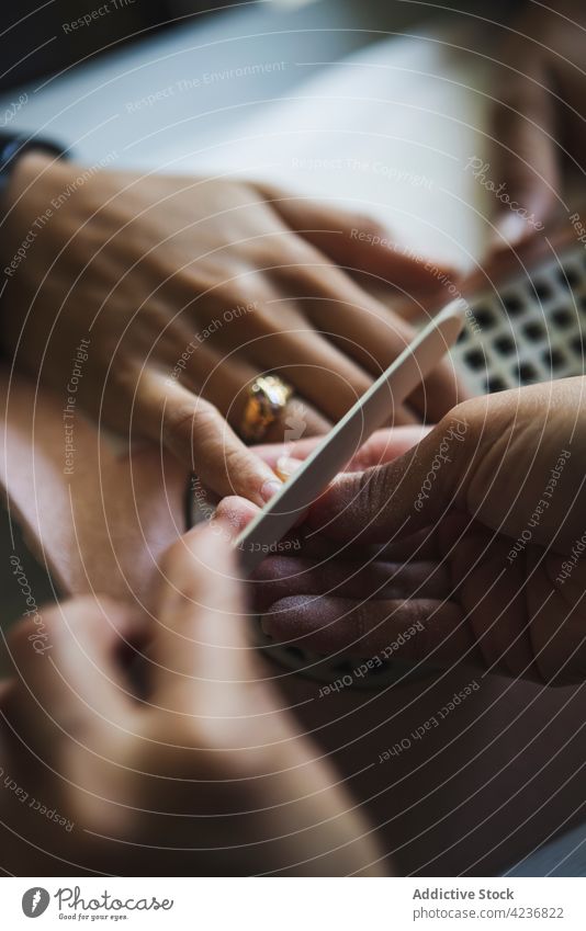 Unbekannter Meister feilt im Studio an den Nägeln einer Kundin Frauen Aktenordner nageln Maniküre Verfahren Leckerbissen Schönheit Klient Salon Spa Job Gerät