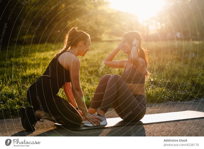 Multiracial fit Frauen tun Übungen im Park Sportlerinnen Training Zusammensein Athlet Unterleib Bauchmuskeln knirschen Hilfsbereitschaft passen Fitness schlank