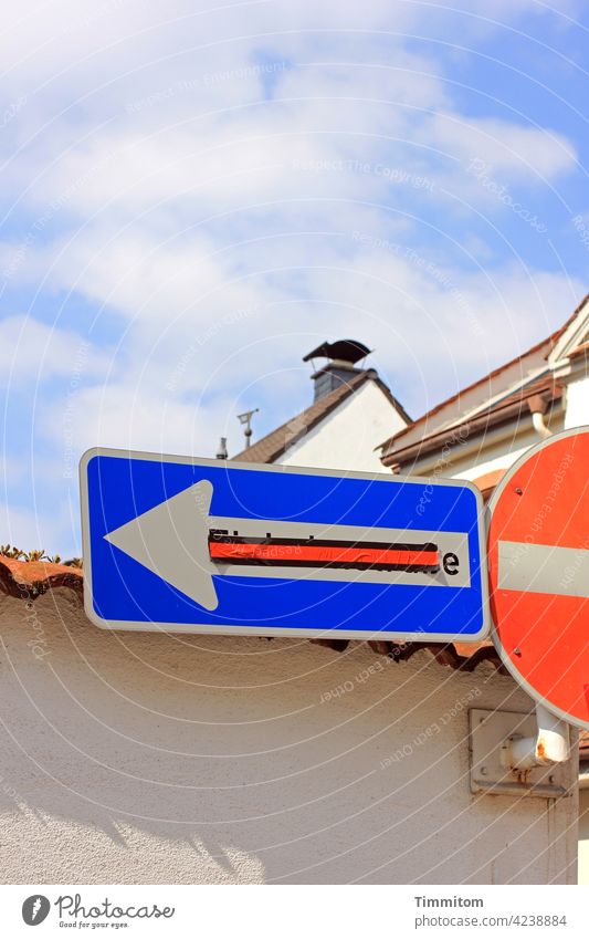 Straßenschilder vor Mauer und Häusern Verkehrsschild Schilder & Markierungen Straßenverkehr Zeichen überklebt rot blau weiß Pfeil