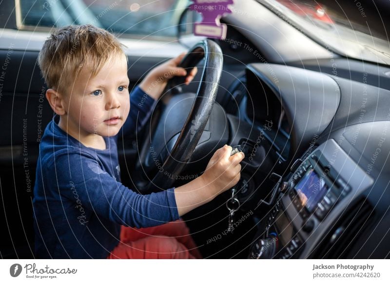 Kleiner Junge sitzt am Lenkrad des Autos PKW Laufwerk Spaß Kleinkind Verkehr Gesicht blond 3-4 Vorschule Fenster Straße lenken Sitz im Freien Familie lustig