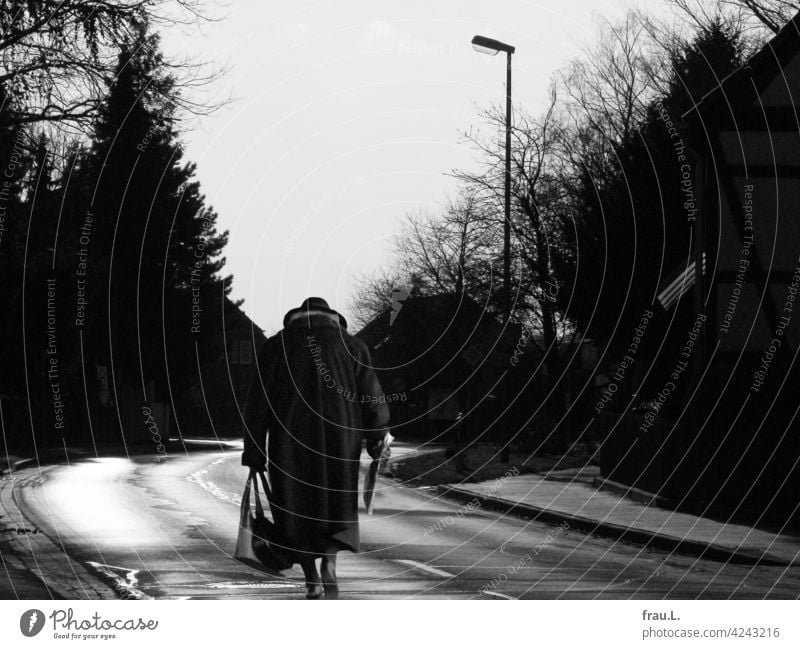 Fast zu Hause Fotomontage allein Mensch Degersen Frau Dorf Hut gehen gebeugt Montage einsam Handtasche Mantel Straße Landstraße Häuser Bäume Dorfstraße Zeitung