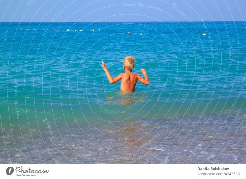 Junge geht sanft mit seinen Händen in das kalte Sommermeer MEER Wasser Kind Lifestyle springen platschen Glück Kinder Spaß werfen Truthahn Menschen Urlaub