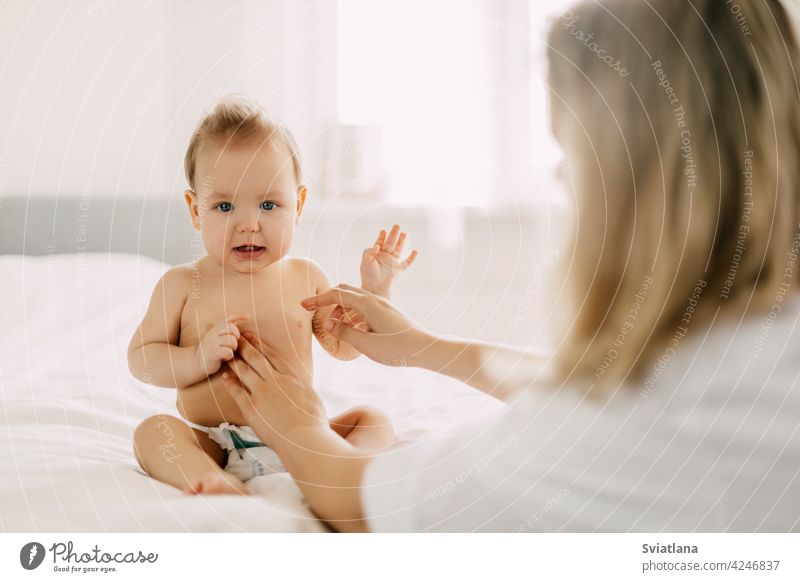 Eine junge Mutter schmiert den Babybauch mit Babycreme ein. Kinderbetreuung, Kindheit, Elternschaft Mama Pflege Sahne Haut Schliere Säugling Kleinkind klein