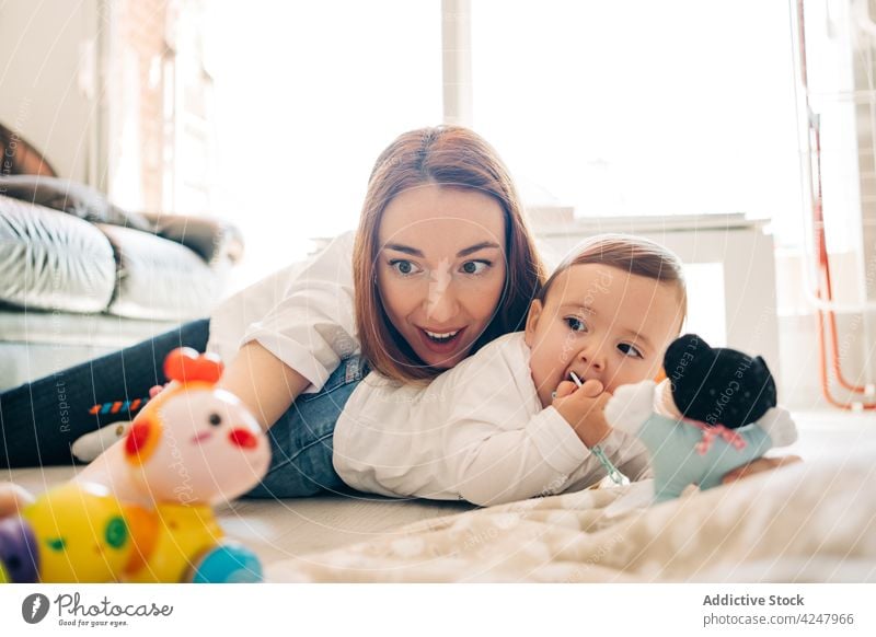 Fröhliche Mutter und Baby spielen auf dem Boden Stock Glück Zusammensein bezaubernd Spaß haben spielerisch freudig Mutterschaft Lächeln wenig Inhalt niedlich