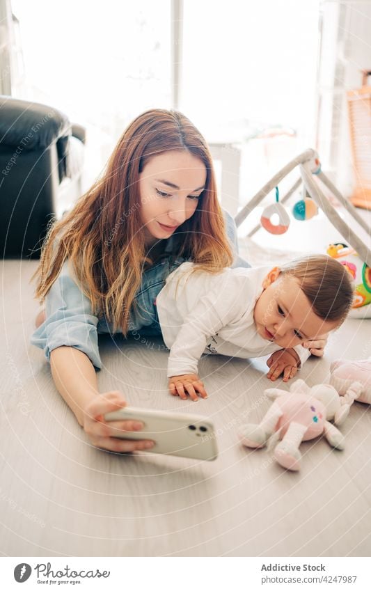 Selbstporträt von Mutter und Baby mit Mobiltelefon Frau Selbstportrait Selfie Smartphone spielerisch Zusammensein Foto zu Hause Mobile Fotografie Gedächtnis