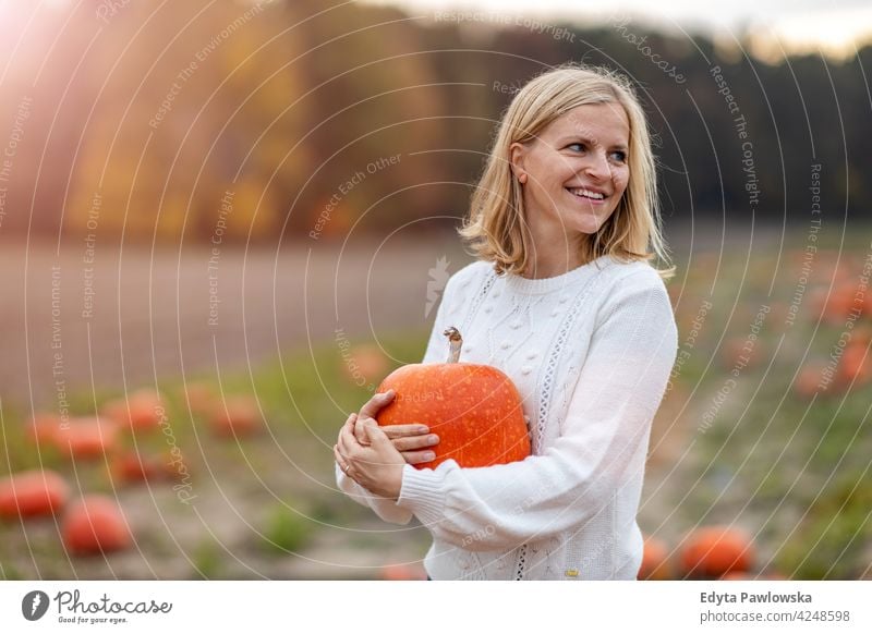 Frau hält Kürbis in Kürbis Patch Feld Halloween Natur Park Herbst fallen Erwachsener jung Menschen Glück Lächeln Spaß Kaukasier genießend Freude im Freien