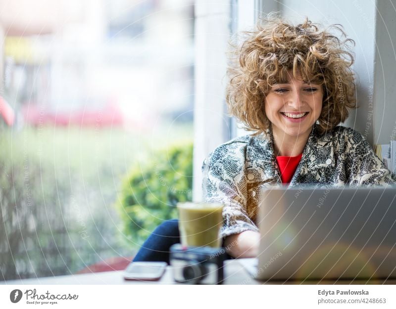 Junge Frau arbeitet an ihrem Laptop im Café genießend Lifestyle jung Erwachsener Menschen eine Person lässig Kaukasier positiv sorgenfrei Glück Lächeln