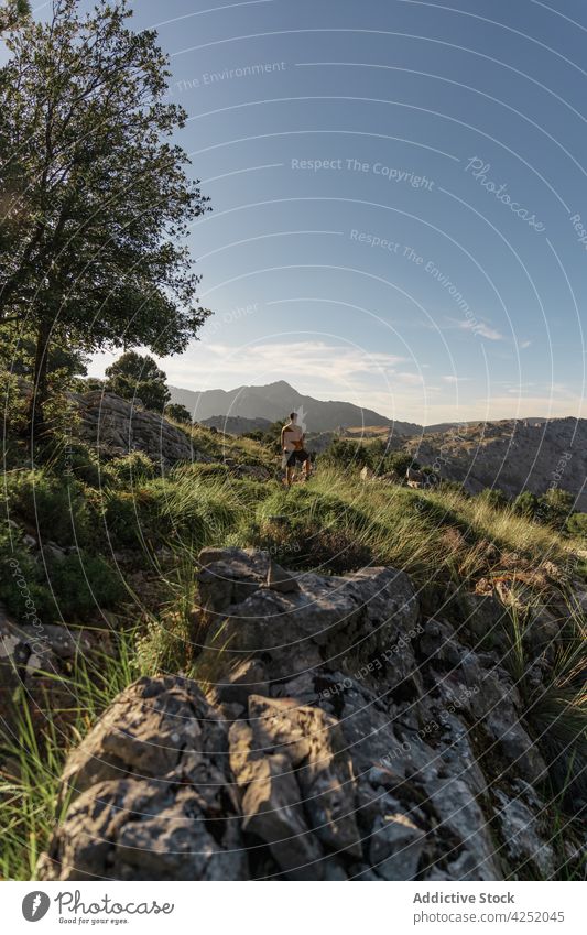 Unerkennbarer Mann ohne Hemd auf einer grasbewachsenen Hügelkuppe in bergigem Gelände stehend Wanderer Berge u. Gebirge Bergkuppe Hochland Bergsteiger