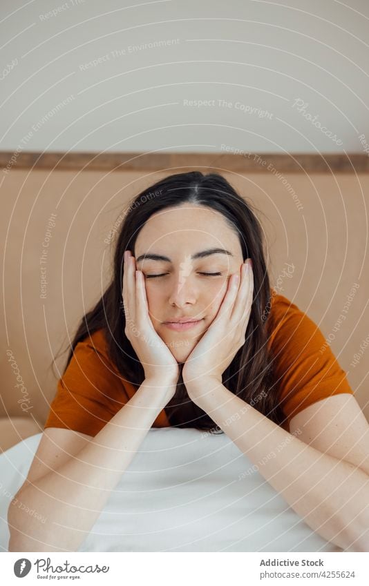 Verträumte Frau sitzt auf einem bequemen Bett am Morgen verträumt sich auf die Hand lehnen Schlafzimmer Komfort Inhalt positiv friedlich Gelassenheit Lifestyle