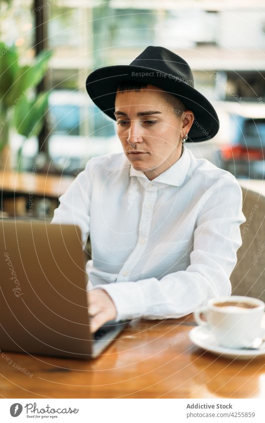 Stilvoller Junge tippt auf einem Laptop, während er in einem Café arbeitet Frau Wildfang benutzend freiberuflich queer maskulin Tippen Browsen abgelegen Surfen