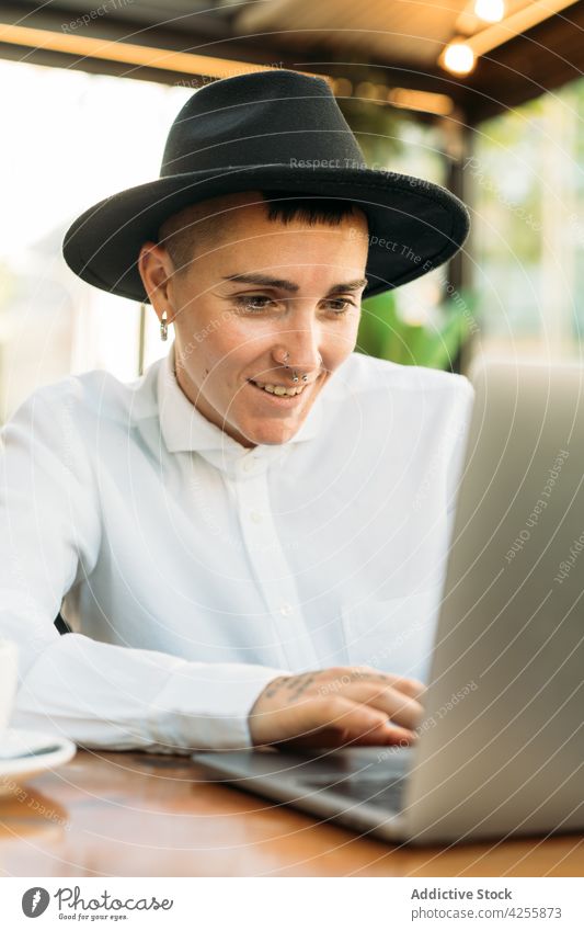 Stilvoller Junge tippt auf einem Laptop, während er in einem Café arbeitet Frau Wildfang benutzend freiberuflich queer maskulin Tippen Browsen abgelegen Surfen