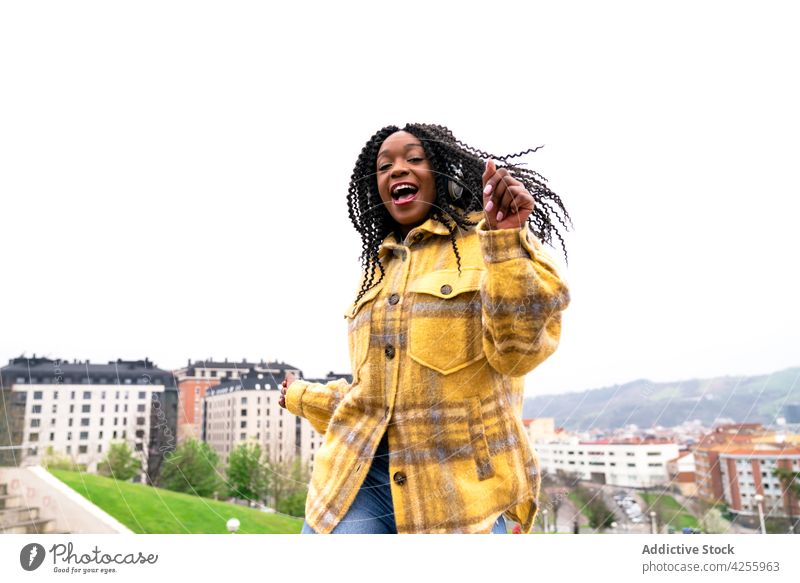 Energetische schwarze Frau tanzt mit der Stadt im Hintergrund Kopfhörer hören sorgenfrei schütteln Tanzen sich[Akk] bewegen Freizeit Musik Freestyle dynamisch