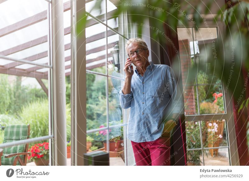 Älterer Mann benutzt Mobiltelefon zu Hause Senior alt Männer männlich heimwärts Menschen Lifestyle genießend häusliches Leben echte Menschen Rentnerin