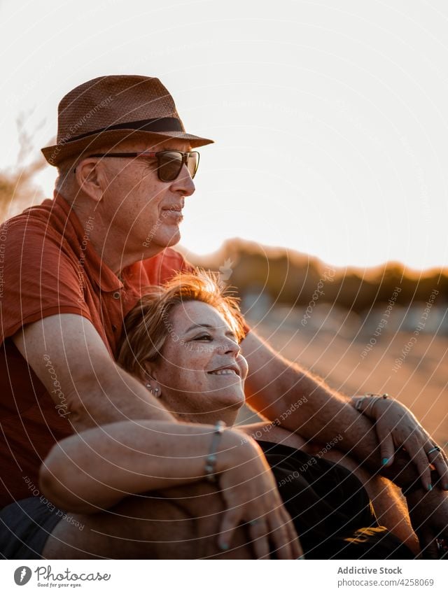 Glückliches Paar, das sich umarmt und am Sandstrand bei Sonnenuntergang ausruht Umarmung Inhalt Meeresufer romantisch Strand Erwachsener Liebe Partnerschaft