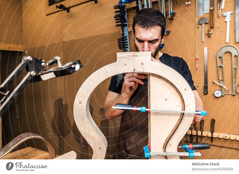 Handwerker baut Gitarre in einer Werkstatt mit verschiedenen Instrumenten Kunsthandwerker bauen Musical Mark Beruf Talent Fähigkeit Schreibstift schreiben