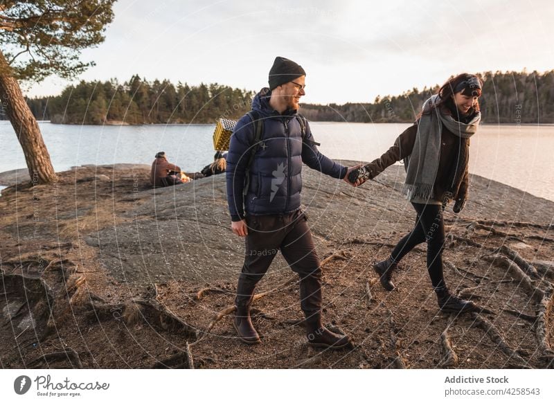 Lächelndes Paar hält sich beim Spaziergang am Ufer an den Händen positiv romantisch Liebe Küste Romantik Natur Fluss Zuneigung Wochenende Freund Freundin froh