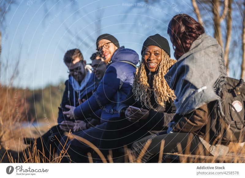 Fröhliche verschiedene Freunde, die sich im Wald unterhalten, während sie sich beim Trekking ausruhen Menschen Talkrunde Lächeln heiter Wanderung Reisender