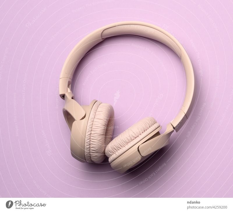 beigefarbene kabellose Kopfhörer auf einem lila Hintergrund Gerät Musik Personal stereo Audio Klang modern Atelier Technik & Technologie Headset digital zuhören