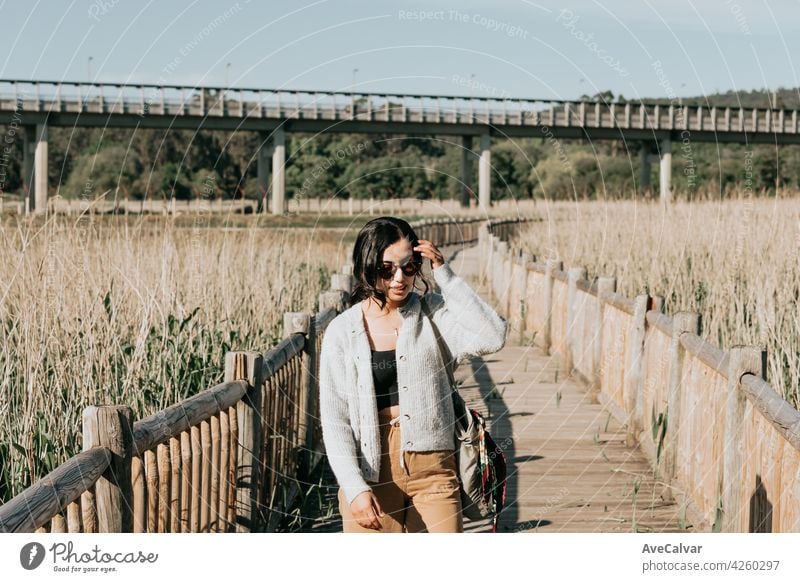 Frau mit Sonnenbrille lächelnd in die Kamera, während auf dem Land Hof während einer super sonnigen Tag mit Kopie Raum und Lifestyle Schuss Person sorgenfrei