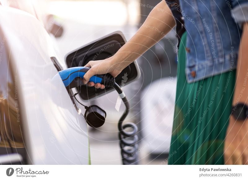 Frau beim Laden eines Elektroautos Aufladen Verkehr Transport reisen Technik & Technologie elektrisch Fahrzeug Elektrizität PKW umgebungsbedingt alternativ