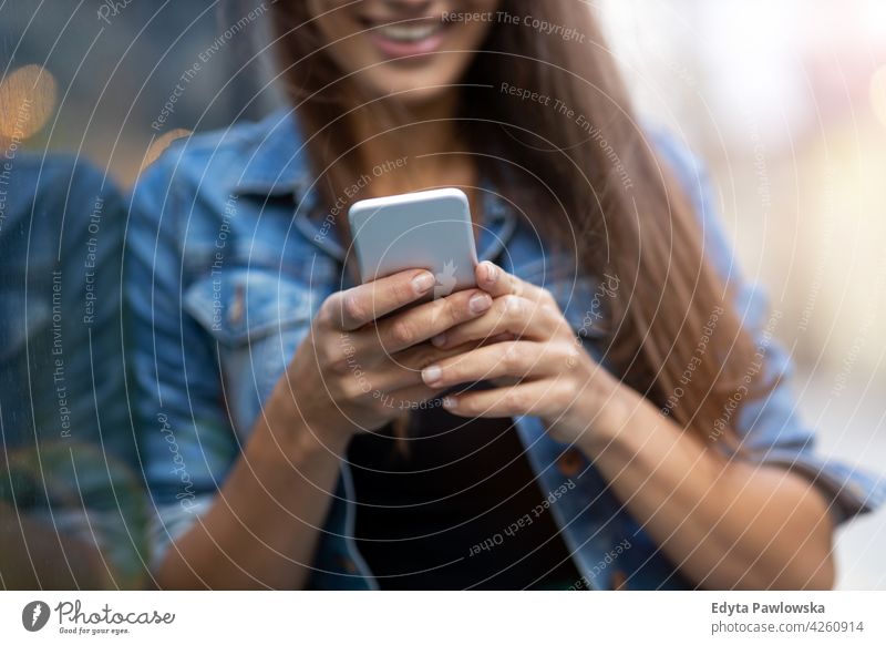 Junge Frau mit Smartphone in einer städtischen Umgebung urban Straße Großstadt aktiv Menschen junger Erwachsener lässig attraktiv Glück Kaukasier genießend