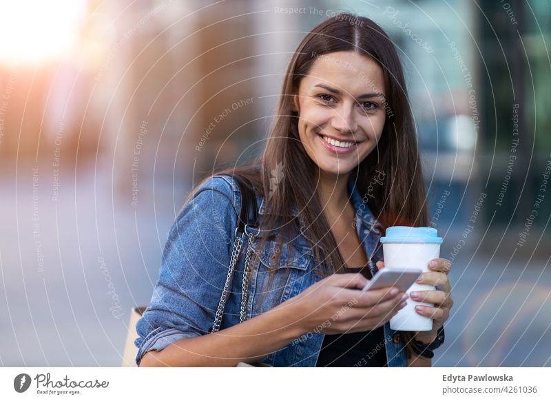 Junge Frau mit Smartphone und Kaffee in der Stadt urban Straße Großstadt aktiv Menschen junger Erwachsener lässig attraktiv Glück Kaukasier genießend