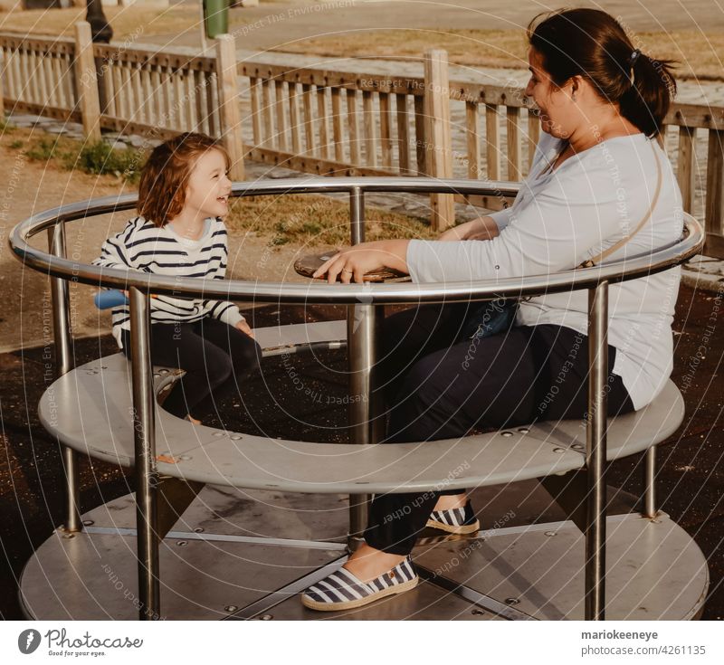 Mutter und Tochter haben Spaß mit einem Spinnrad auf einem Kinderspielplatz Spaß haben Mittäterschaft Frauen Zwei Personen Spielen Farben im Freien Mädchen